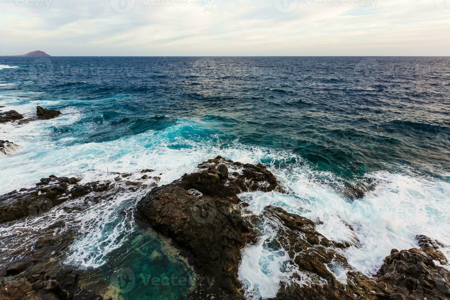 ocean waves hit and crash against stones photo