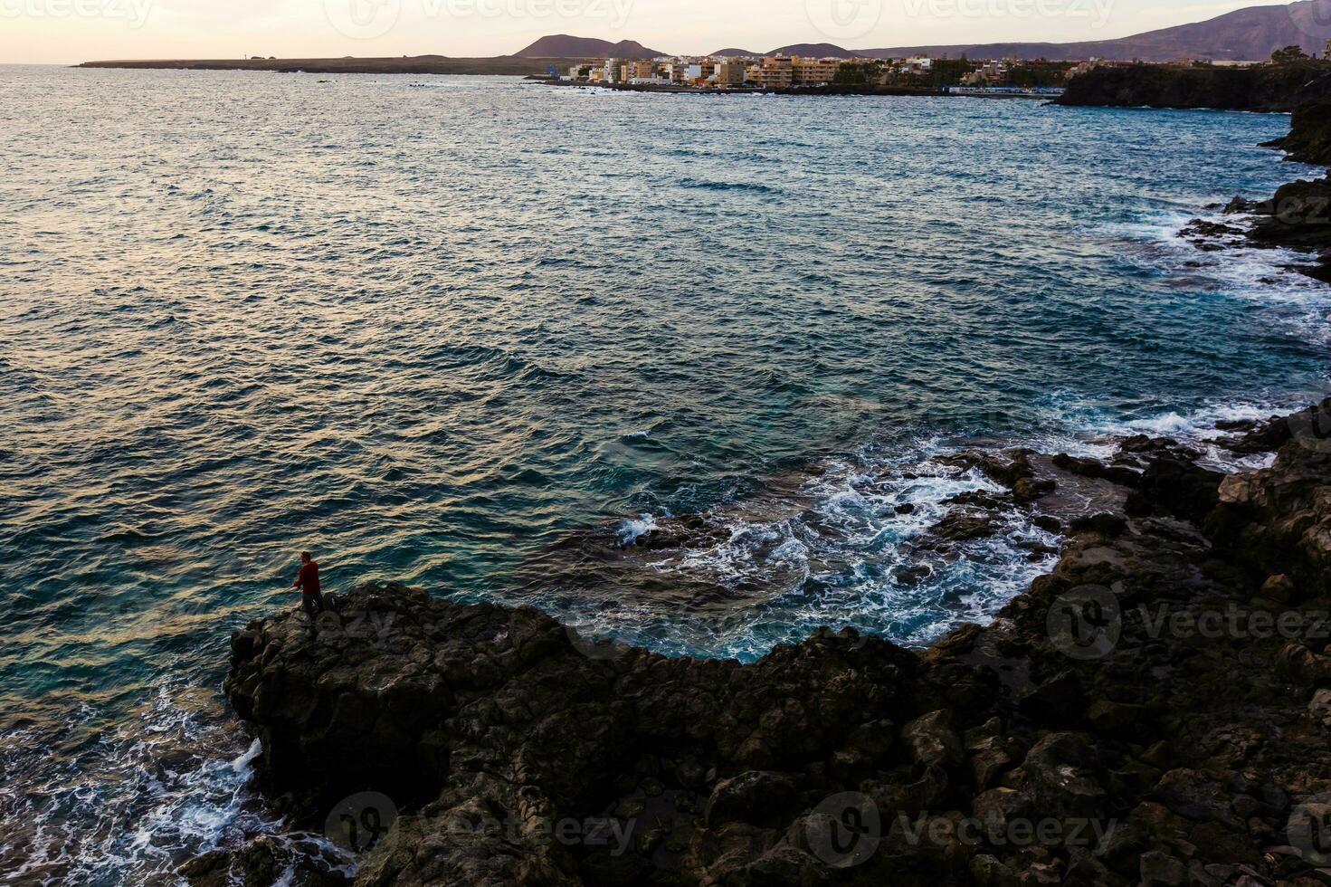 marina con atlántico Oceano y el cielo a crepúsculo, piedras en el playa y pescadores en el muelle. largo exposición con borroso mar agua foto