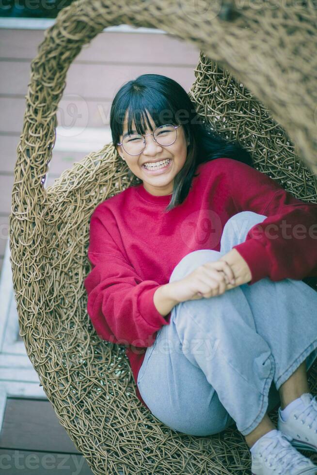 asian teenager toothy smiling with happiness face ,relaxing on bamboo cradle. photo