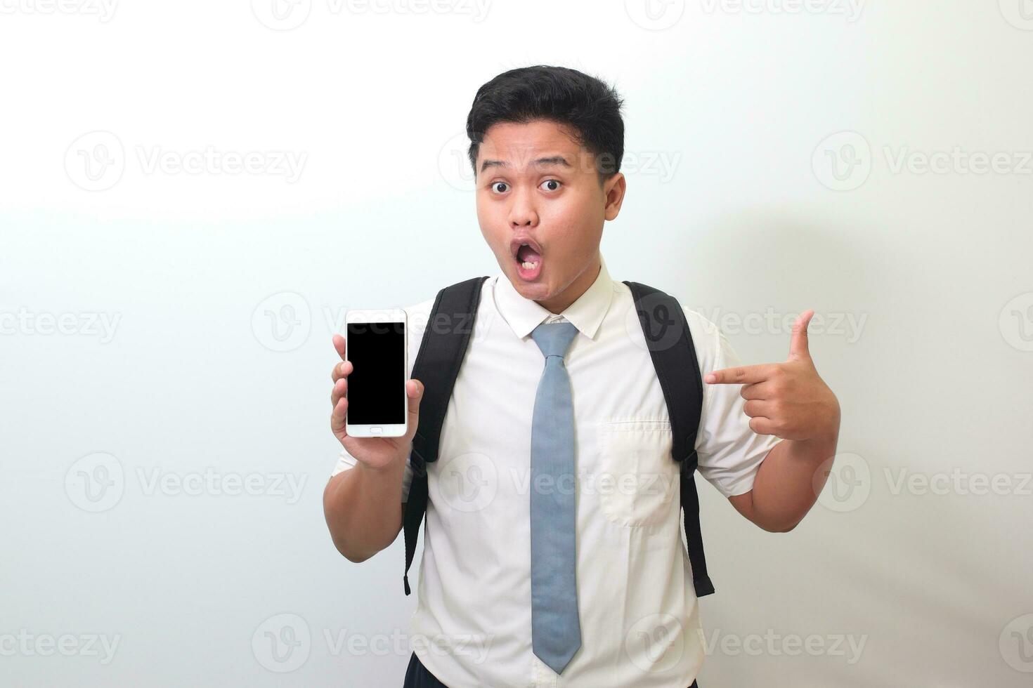 Indonesian senior high school student wearing white shirt uniform with gray tie showing and presenting blank screen mobile phone. Isolated image on white background photo
