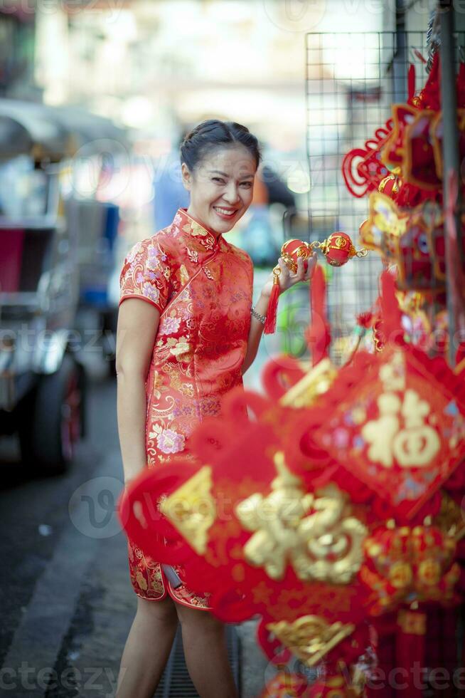 asiático mujer vistiendo chino tradicion ropa con chino bambú ventilador sonriente cara en yaowarat calle China pueblo de Bangkok Tailandia foto