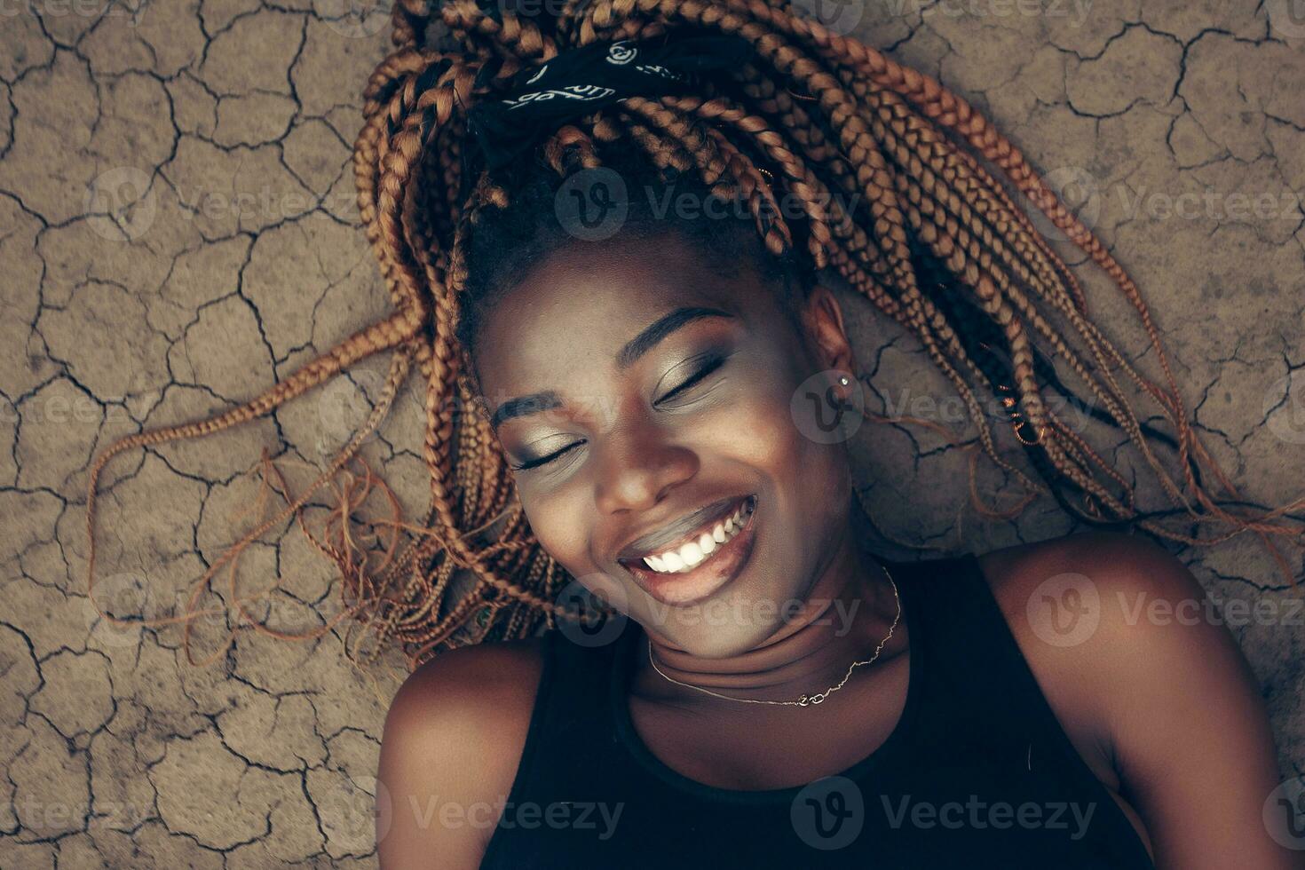 Beautiful African female on dry cracked ground in the desert photo