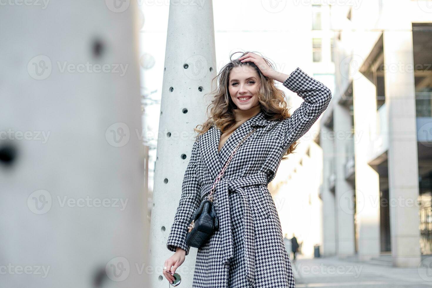 Attractive girl in a coat in the street in a city, sun is shining photo