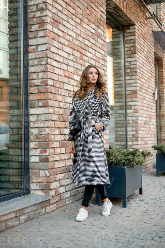 Attractive girl in a coat in the street in a city, sun is shining photo