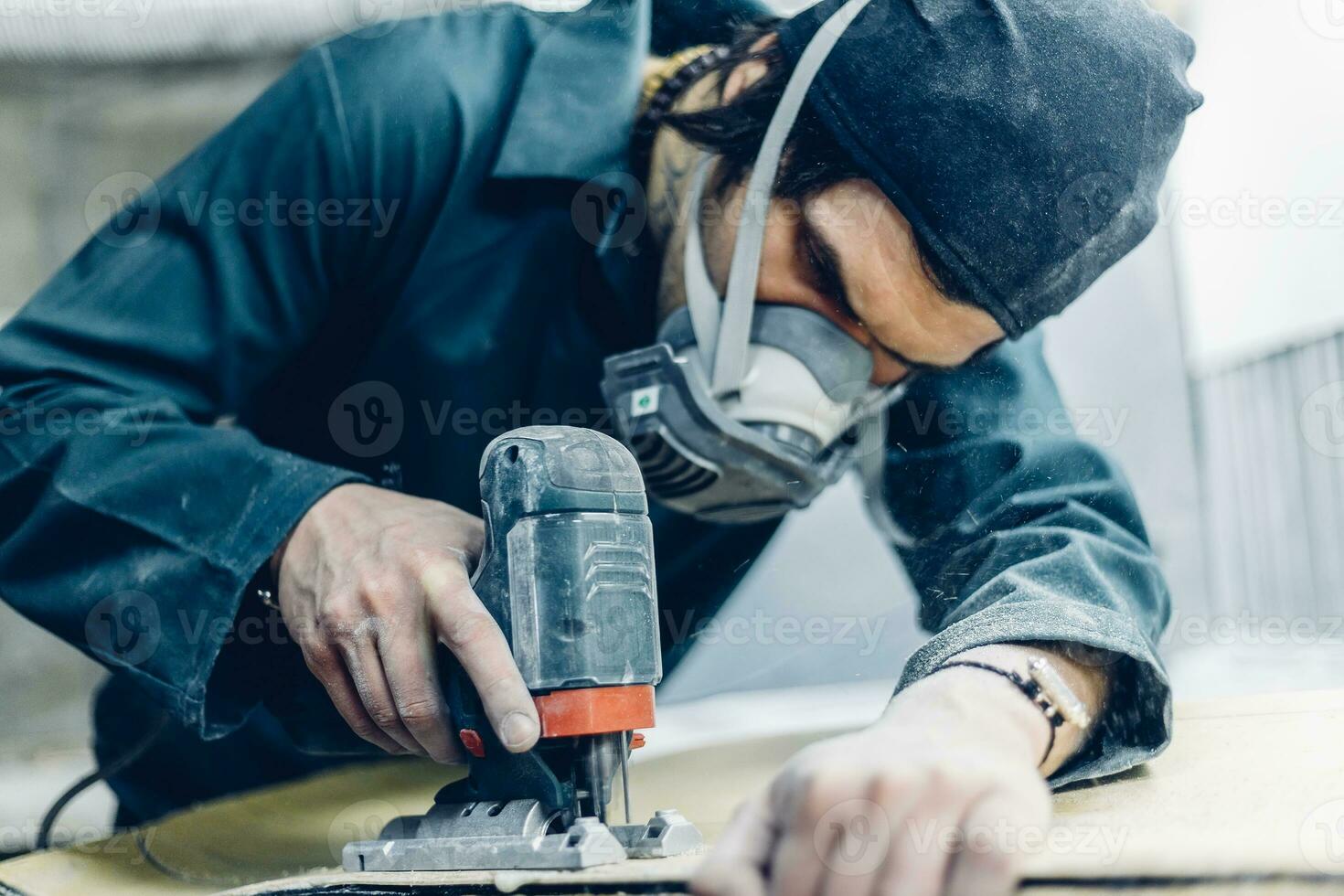 A carpenter cuts a board with an electric jigsaw. photo