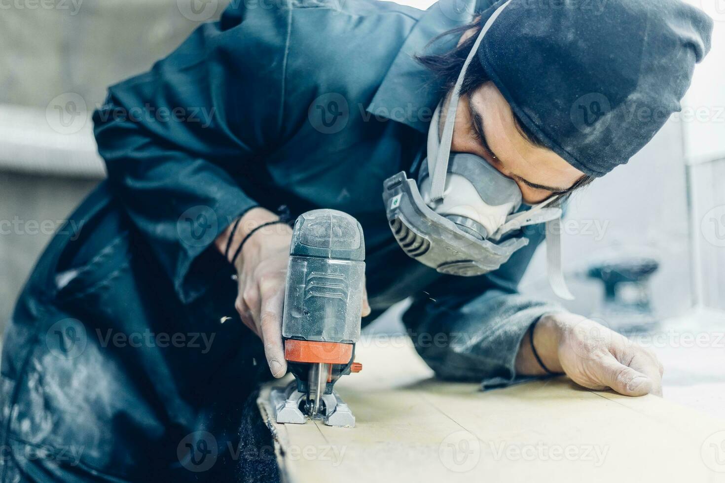 A carpenter cuts a board with an electric jigsaw. photo