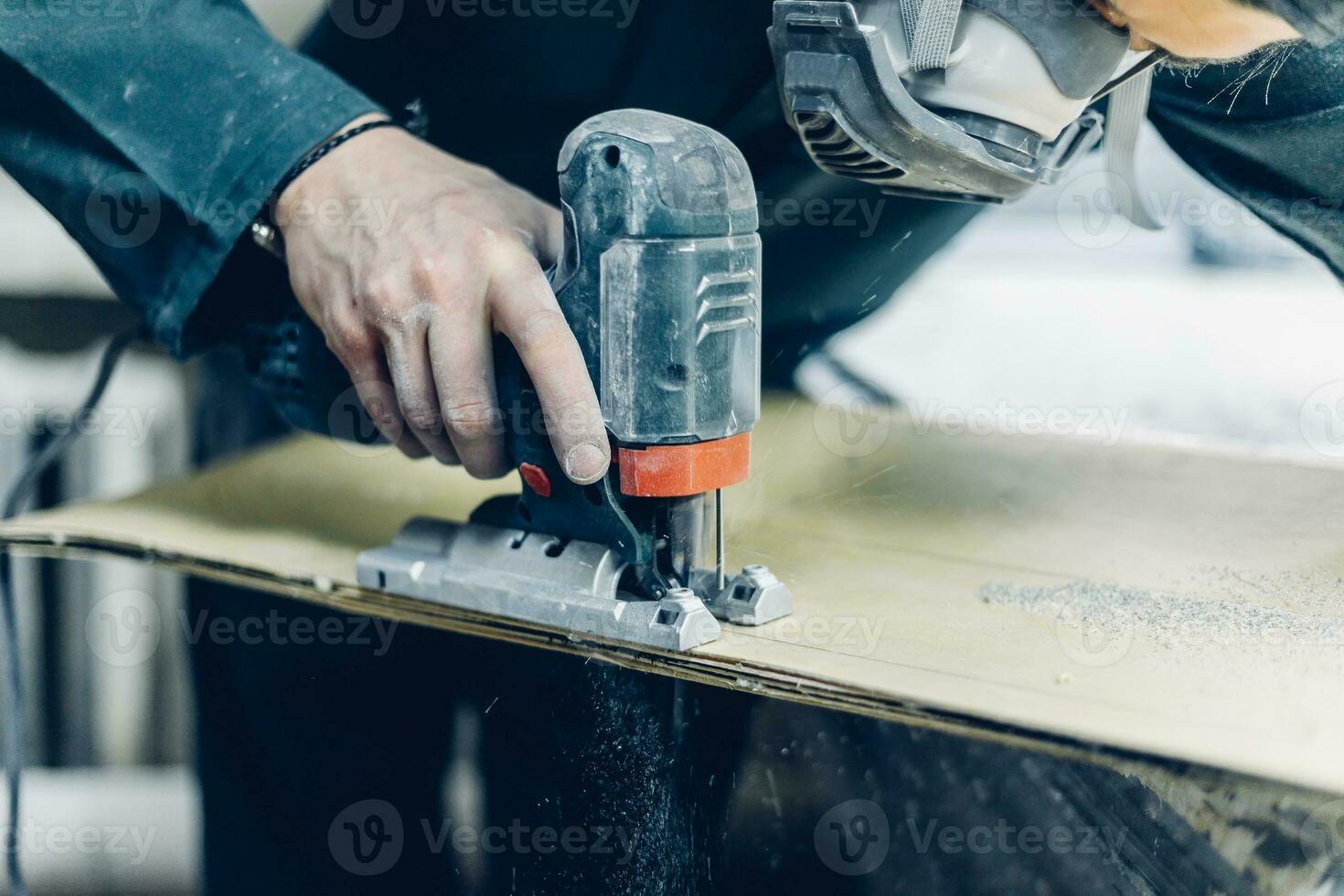 A carpenter cuts a board with an electric jigsaw. photo