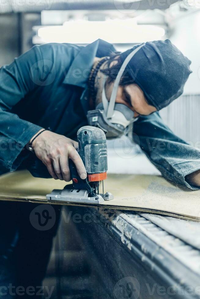 A carpenter cuts a board with an electric jigsaw. photo