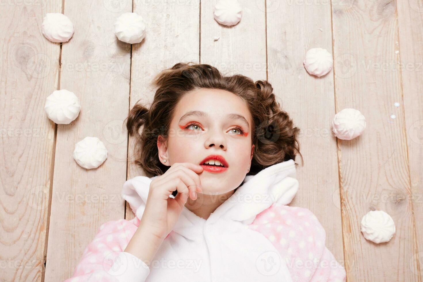 linda pequeño niña en pijama con dulces sentado en el piso foto