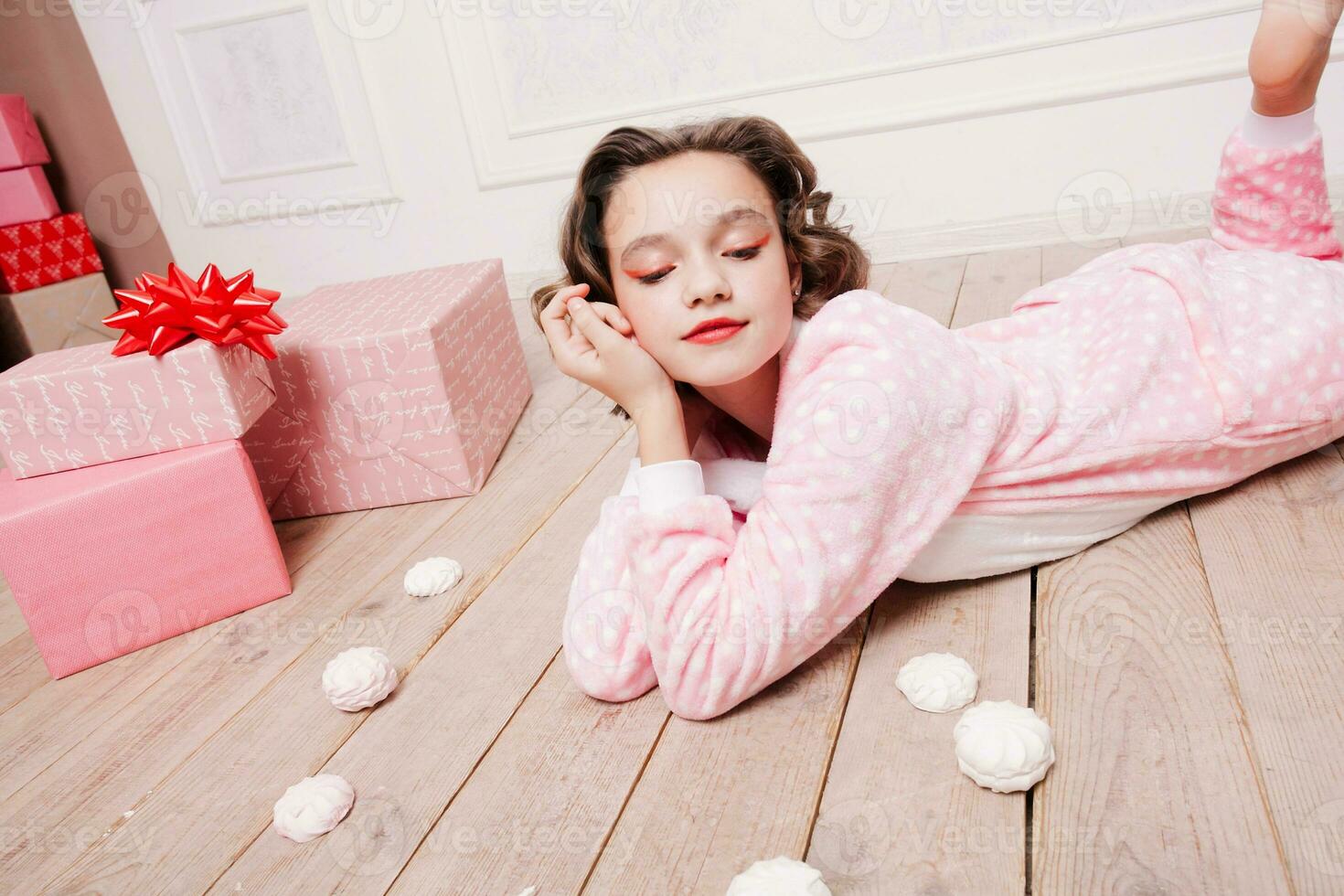 Cute little girl in pajama with sweets sitting on the floor photo