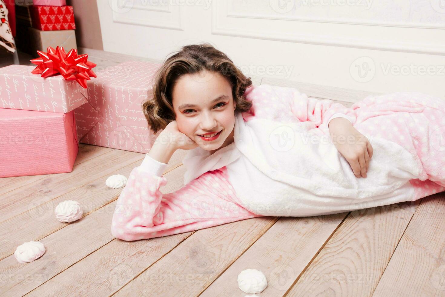 Cute little girl in pajama with sweets sitting on the floor photo