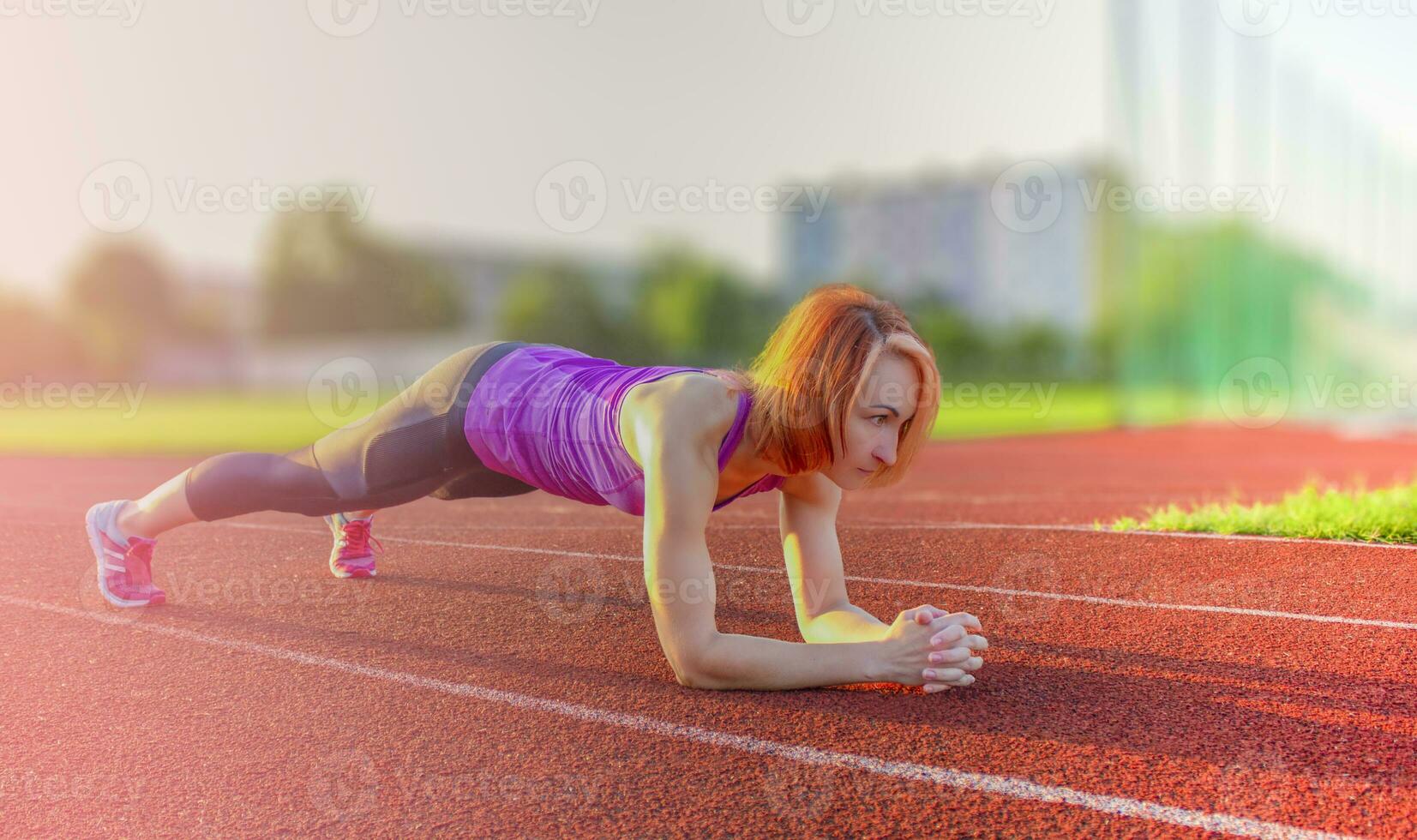 A beautiful, athletic woman trains on the sports field. photo