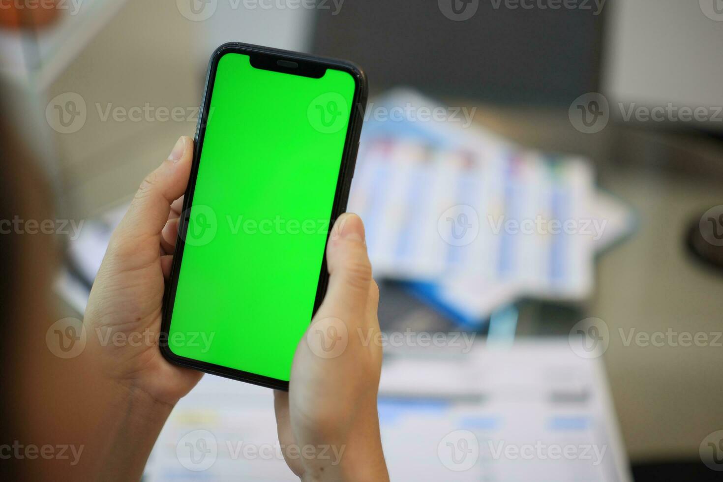 Phone green screen in hand, hand holding smartphone green screen in house, using mobile phone green screen photo