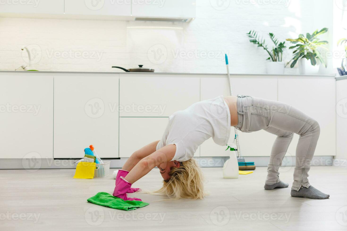 housewife kneeling down on the wooden floor holding cloth wearing gloves and apron resting. exhausted woman tired after doing housework prepared new year holidays. cleaning products in bucket photo