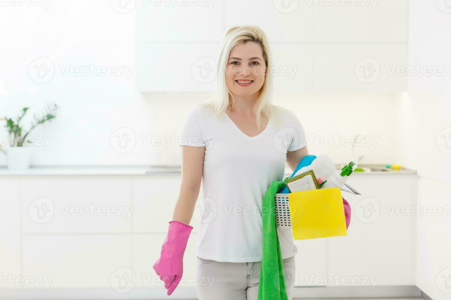 Young blond woman washes the oven in the kitchen. Protective rubber gloves on her hands photo