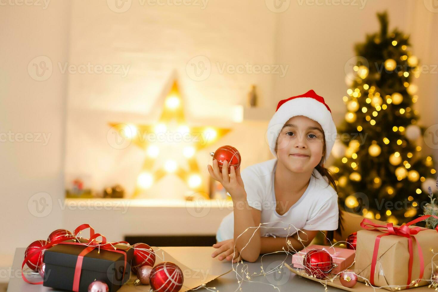 child girl in red hat preparing gifts for christmas at home, cozy holiday interior photo