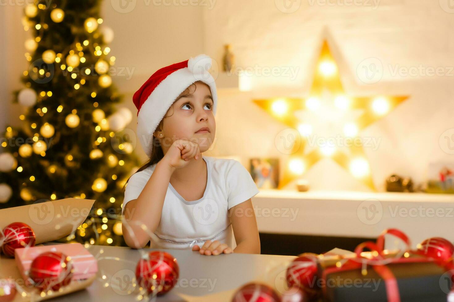 child girl in red hat preparing gifts for christmas at home, cozy holiday interior photo