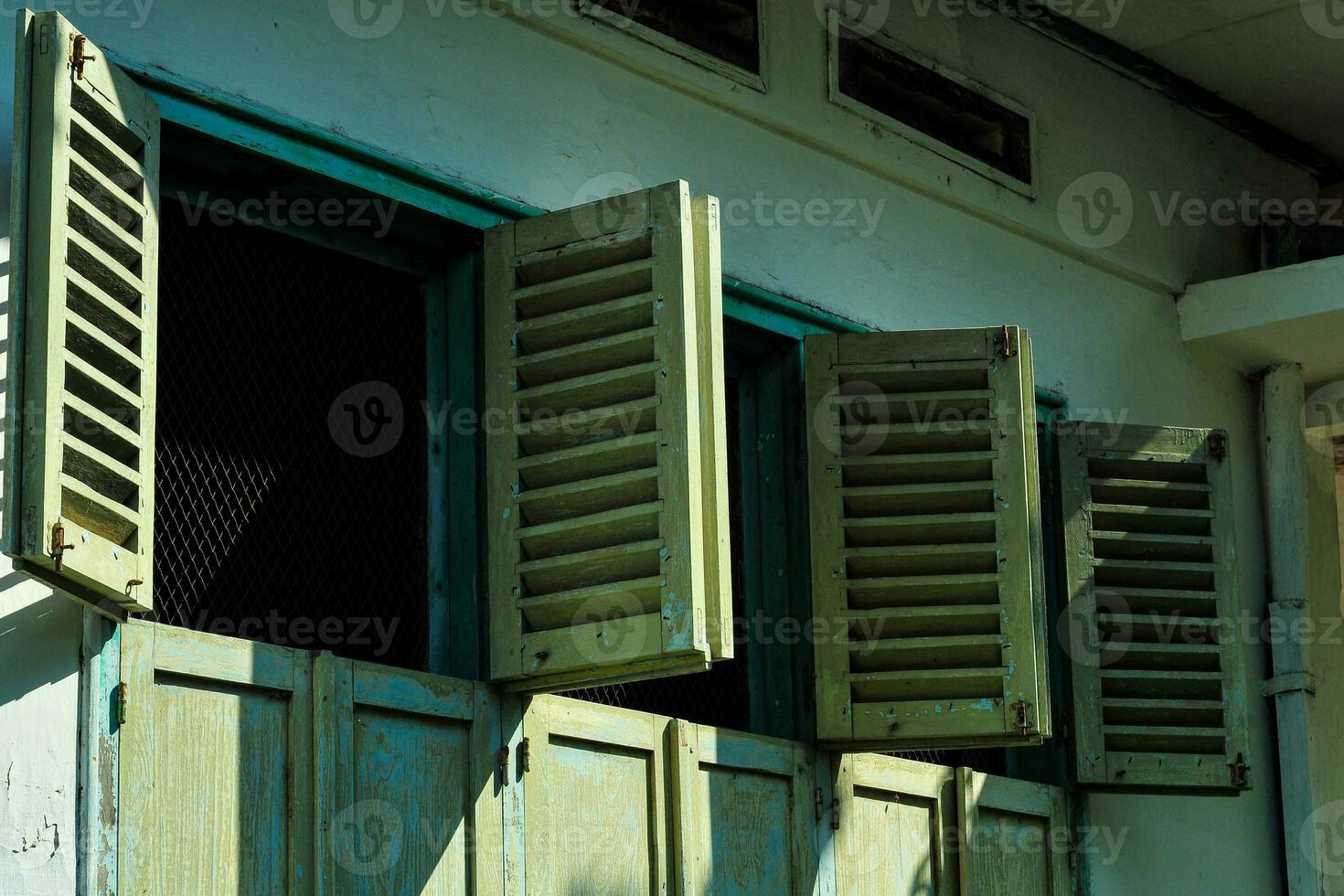 the design of an open window from an old, dull teal-colored house. photo