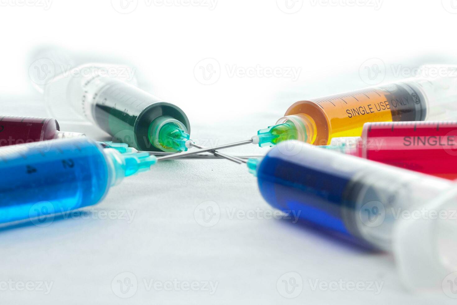 Syringes filled with colorful liquids are neatly arranged on an isolated background photo