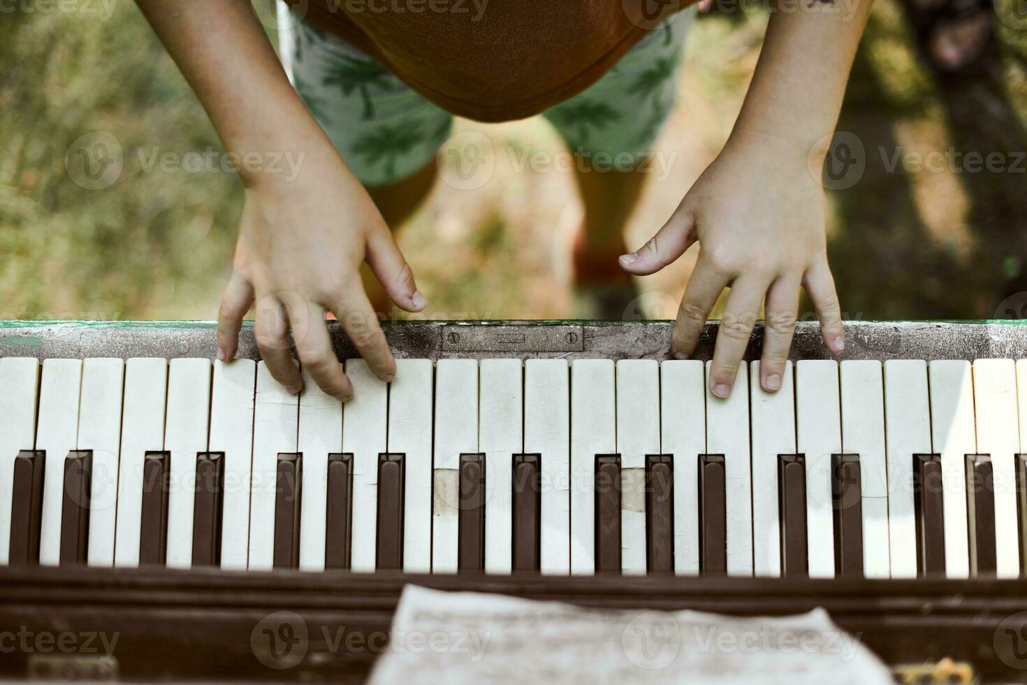 Little boy hands playing on piano keyboard above view close up, children art hobby play music photo