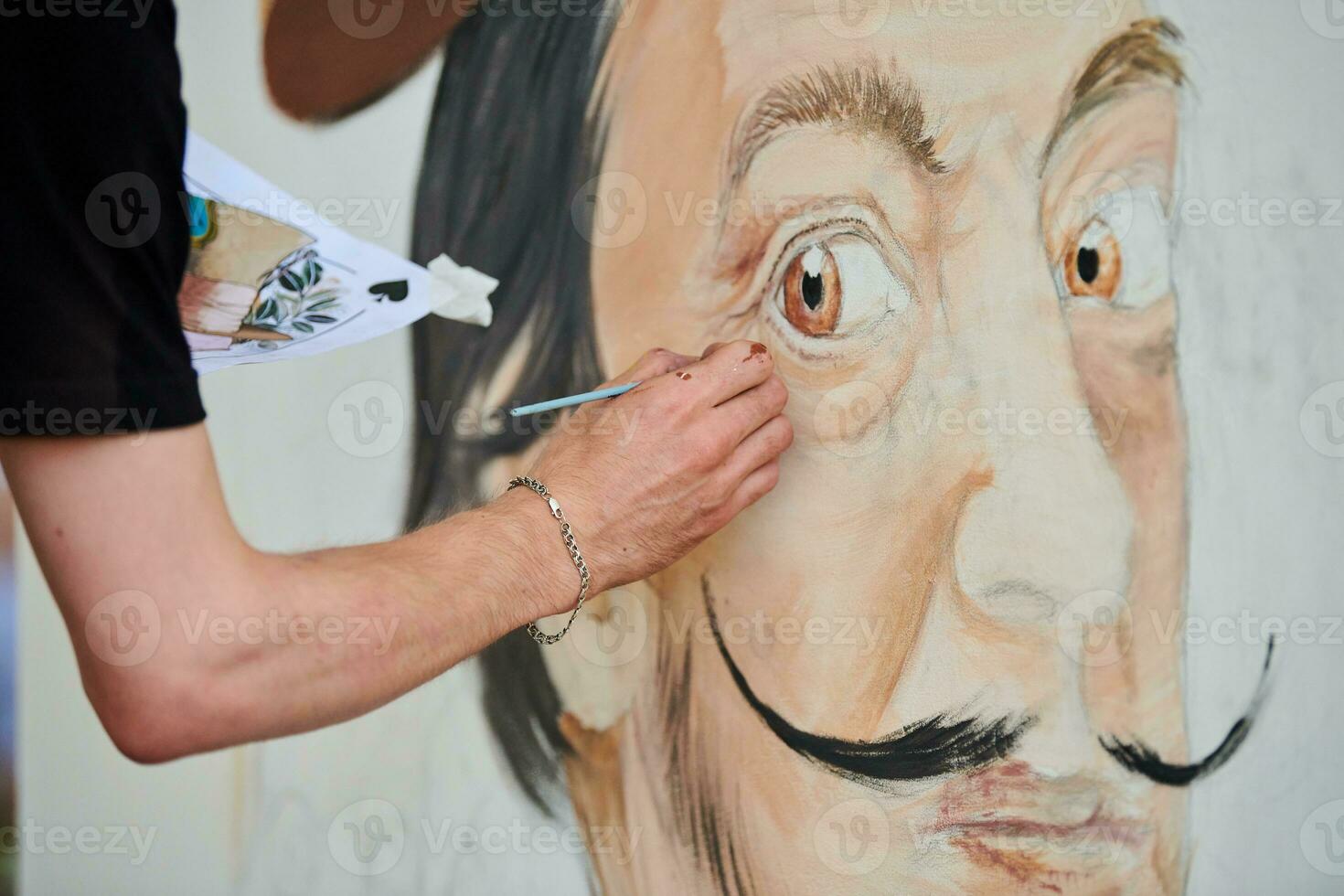 Young man artist draws with paint brush surreal man portrait on white canvas art painting festival photo