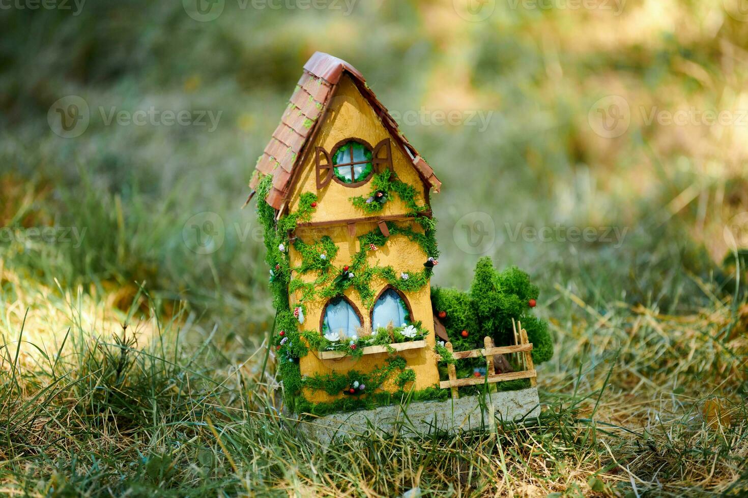 Little dollhouse on front lawn, cute small decorative house on green grass field, copy space photo