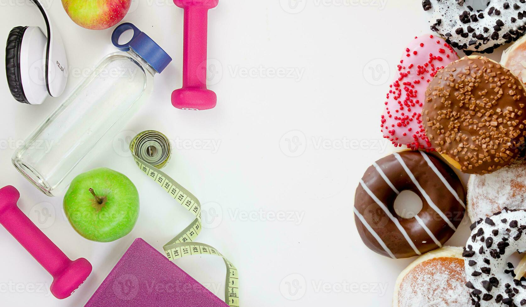 Choose between a healthy lifestyle and junk food. Dumbbells, tape measure, apple, bottle and donuts on a white background. photo