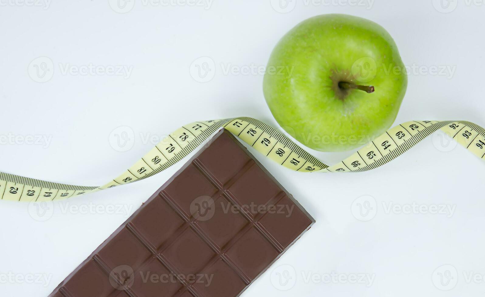 Choose between a healthy lifestyle and junk food. Apple centimeter ribbon and chocolate on a white background photo