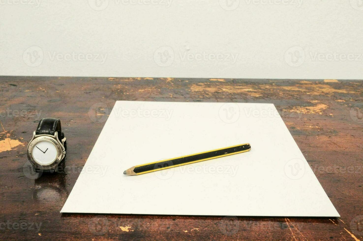 a pencil and a watch on a table photo