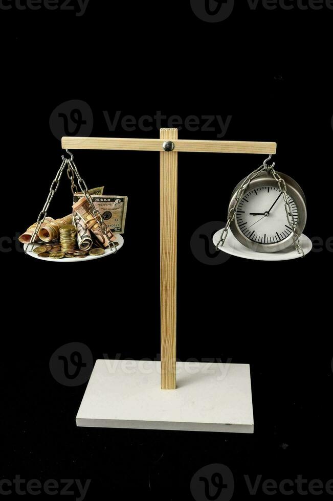 a clock and money on a scale with a black background photo