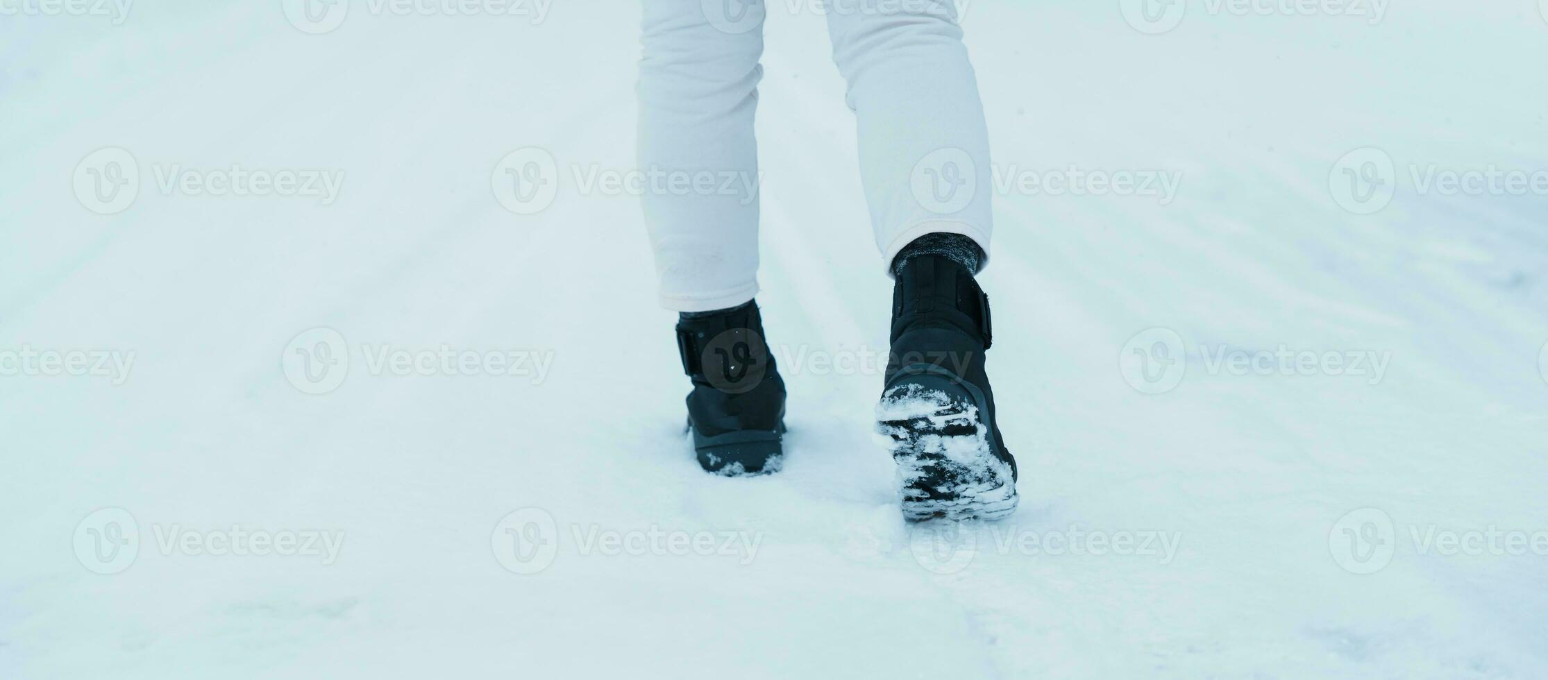 traveler walking on the snow,  closeup waterproof boots or shoes during hiking on snowy forest. Winter season photo