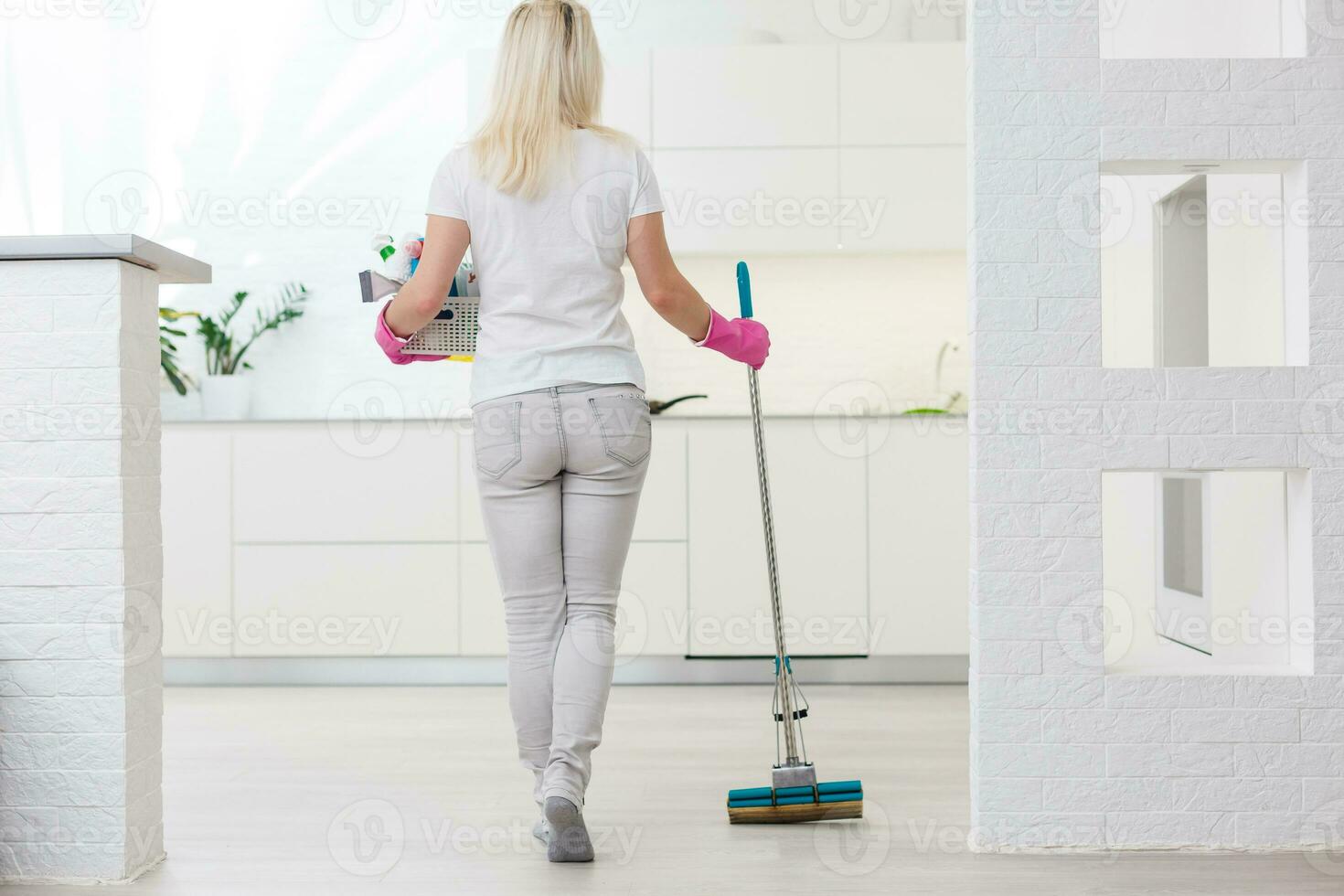 Woman holding mop and bucket with cleaning agents at home photo