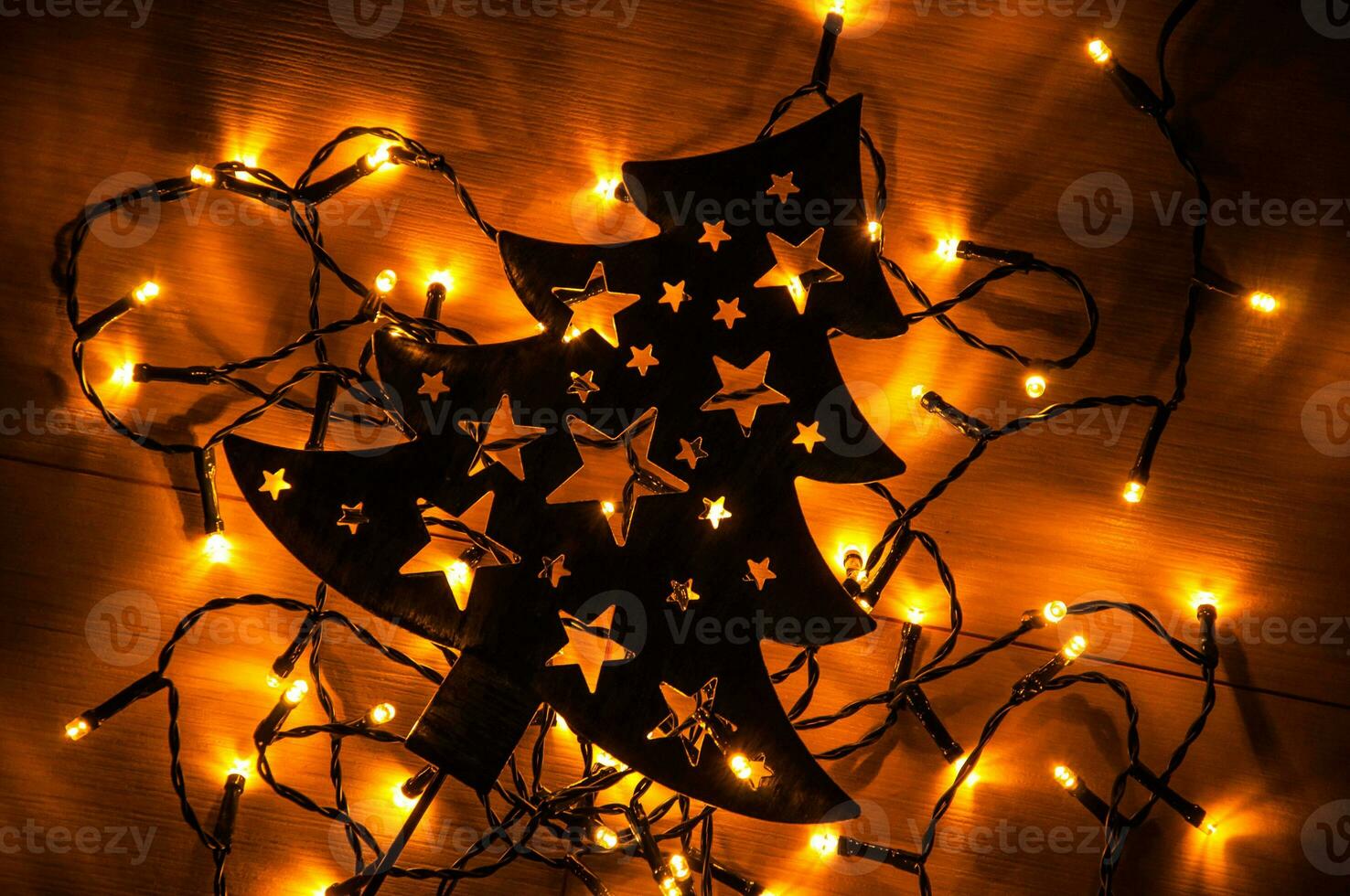 Black Christmas tree on the wooden background with small yellow Christmas lights photo