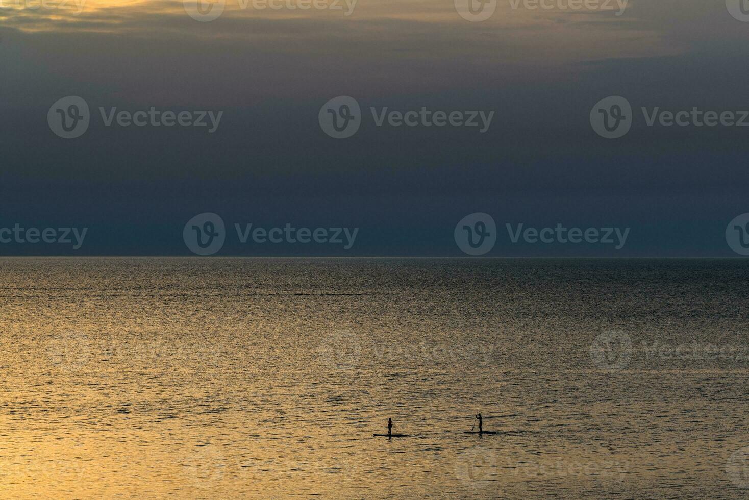 Surfers on the calm sea during the sunset photo
