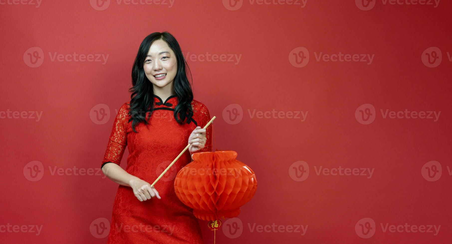 Asian chinese woman with red cheongsam or qipao holding denglong the paper lantern to wish the good luck and prosperity in Chinese New Year celebration holiday isolated on red background photo