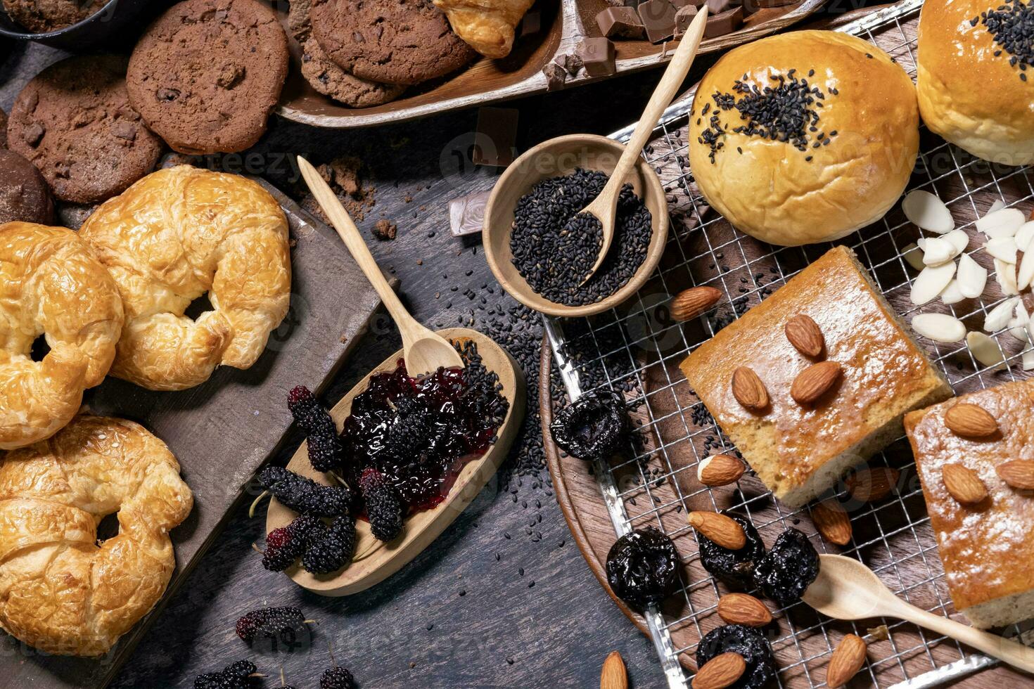 Table top view of organic rustic style bakery with whole grain bun, bread and cookies with various berry and nut for homemade healthy pastry and traditional baking bread concept photo