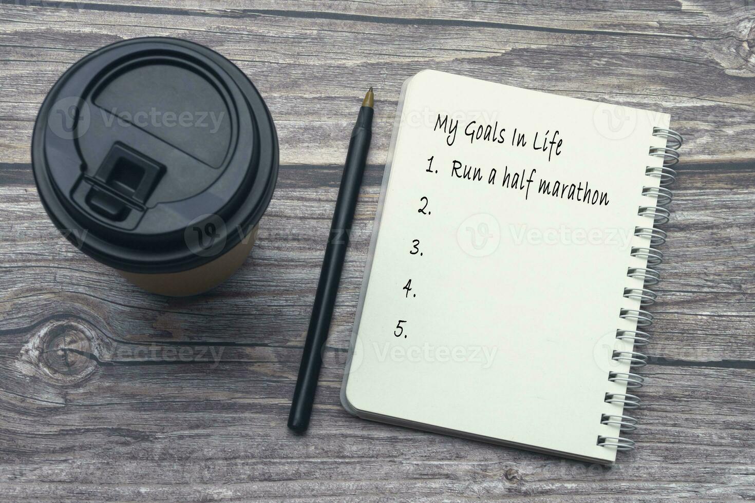 My goals in life list on notepad with pen and coffee on wooden desk. photo