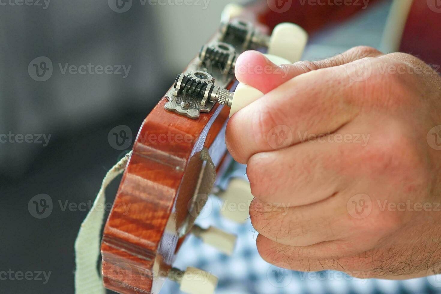 close-up of a man twisting Tuners or Tuning pegs. photo