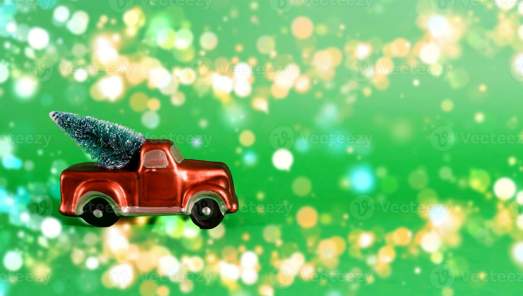 New Year card with place for text. Red car with a Christmas tree in the back of a pickup truck on a green background with blurry bokeh photo