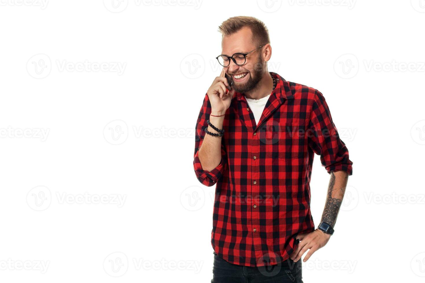 Portrait of a casual young man speaking on the phone and smiling while looking away, somewhere up. Studio shot on white background photo