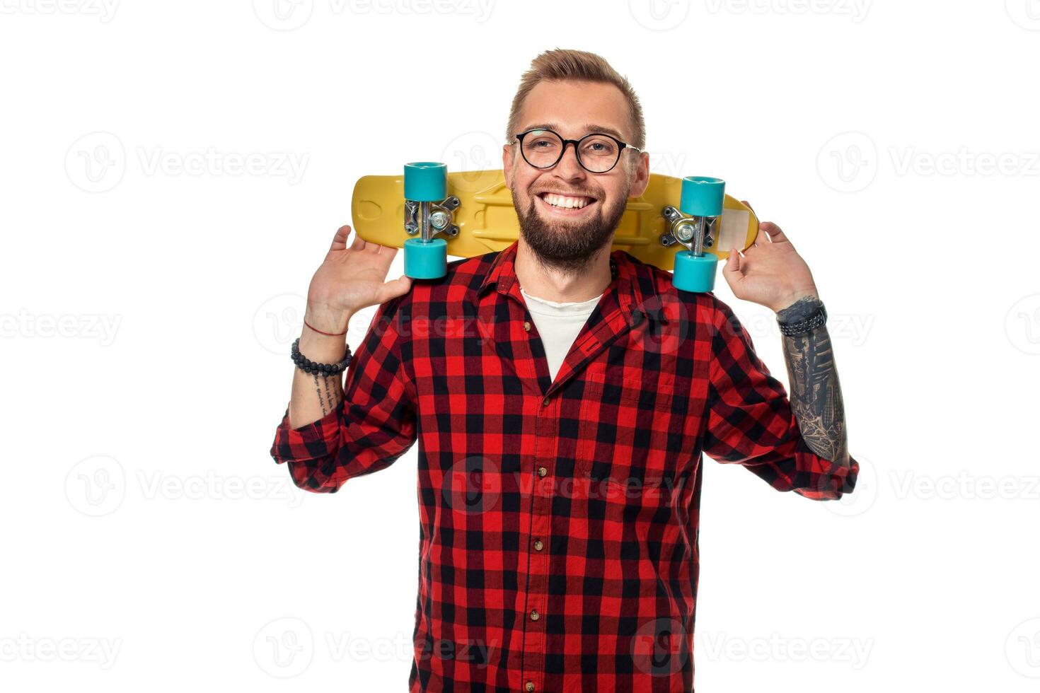 Hipster man over white background holding yellow skateboard. Active guy in plaid shirt with copy space photo