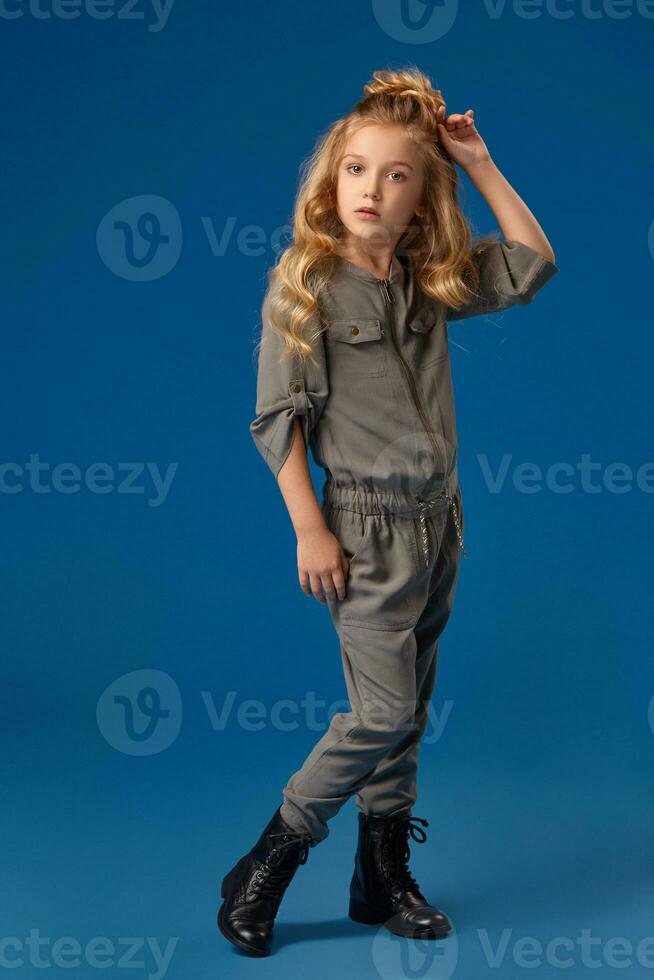 pequeño niña en un de moda ropa en azul antecedentes foto