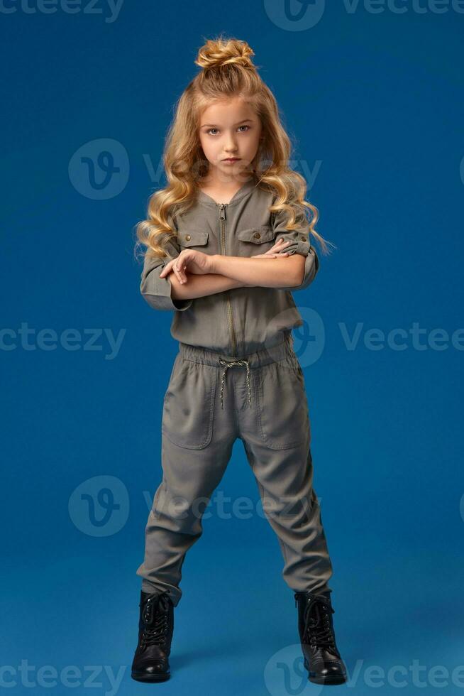 pequeño niña con un largo Rizado pelo en un de moda ropa foto