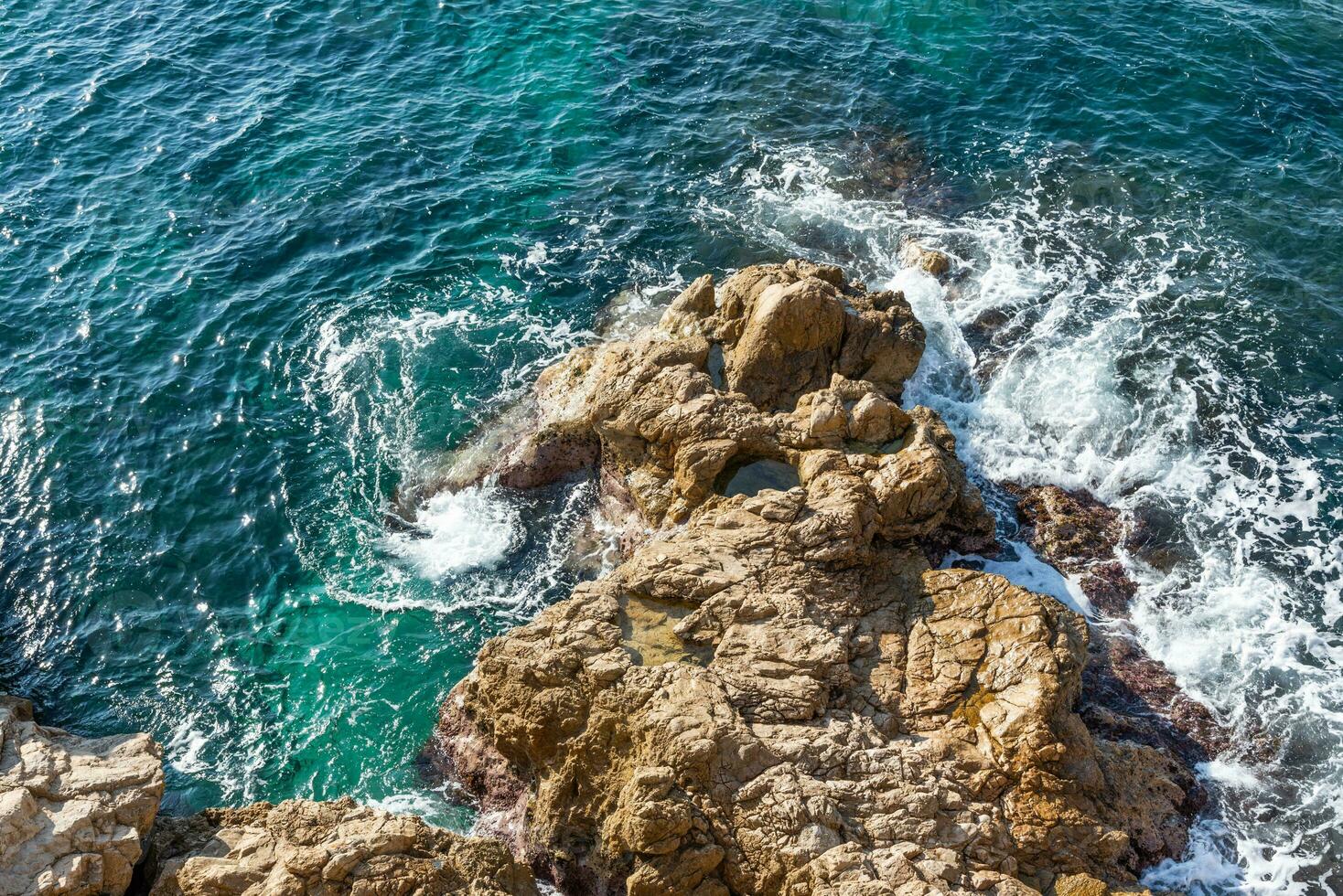 Clear waves of Mediterranean sea hitting the rocks of Marseille photo