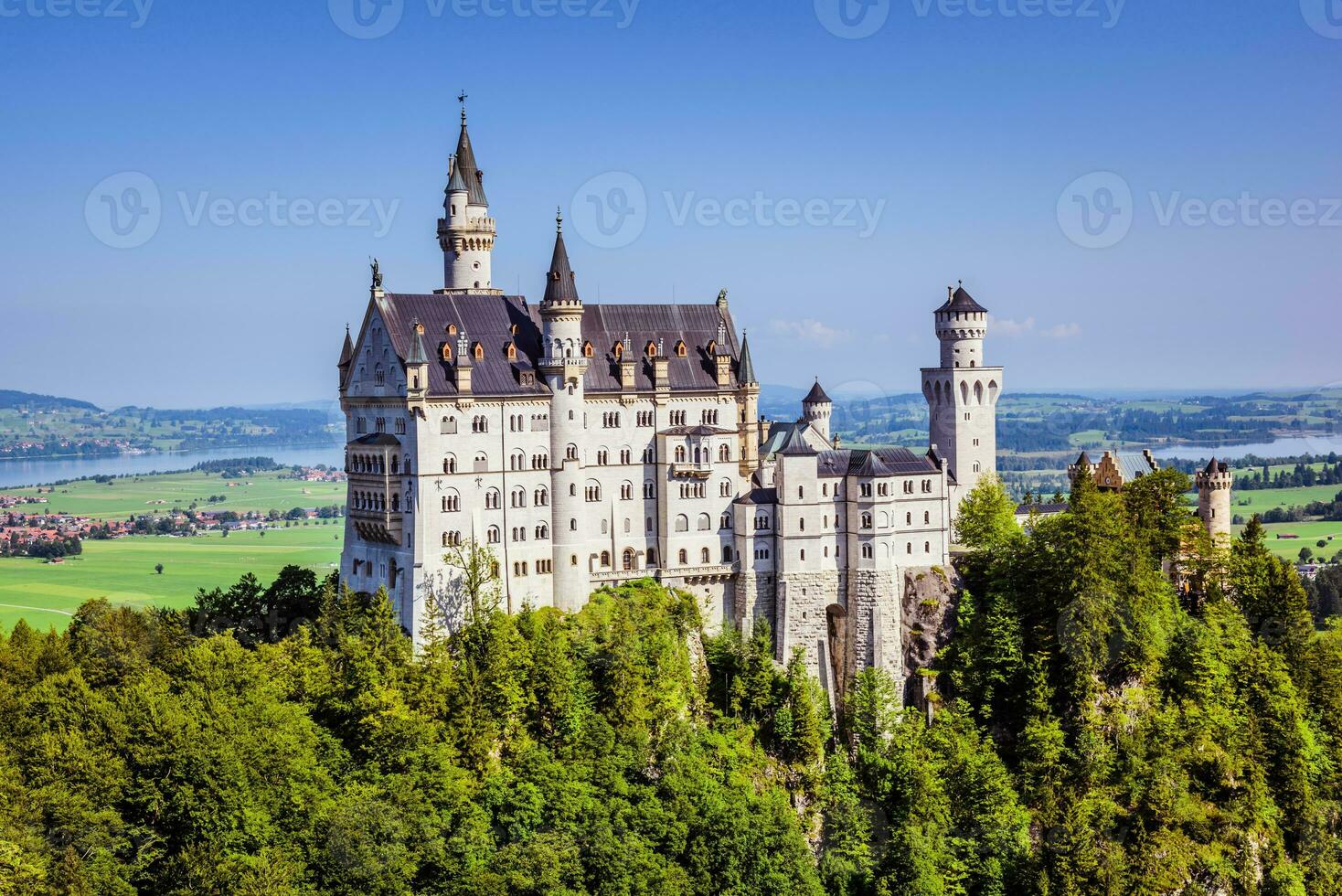 Neuscwanstein castle on the mountain with green fields and blue sky on the background photo