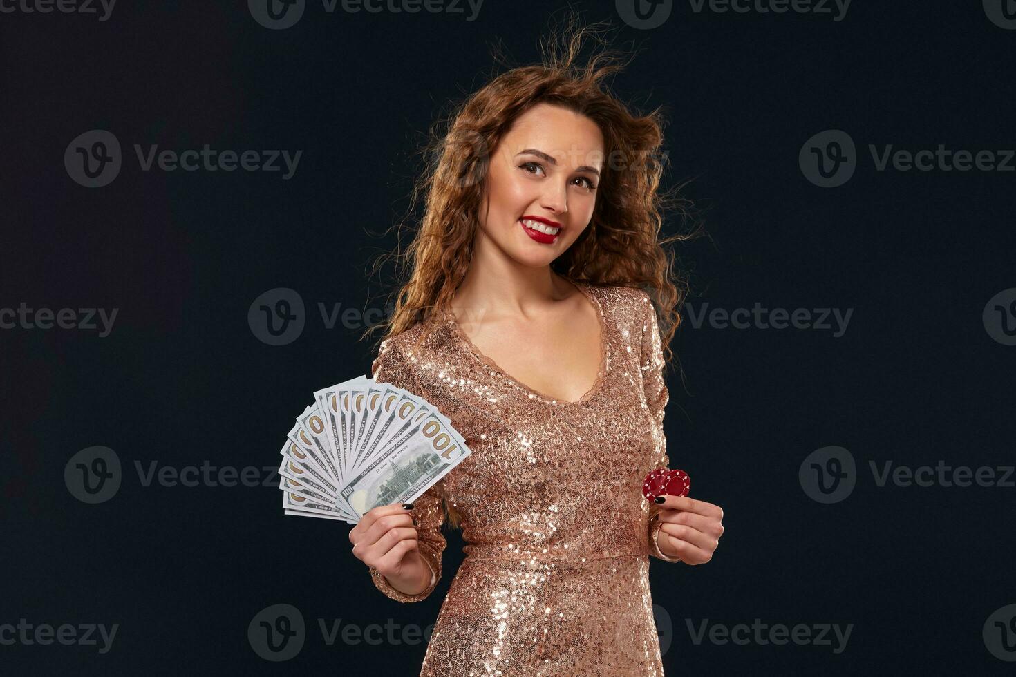 Image of lucky happy woman with brown long hair with fan of 100 dollar bills, lots of cash money, over black background photo