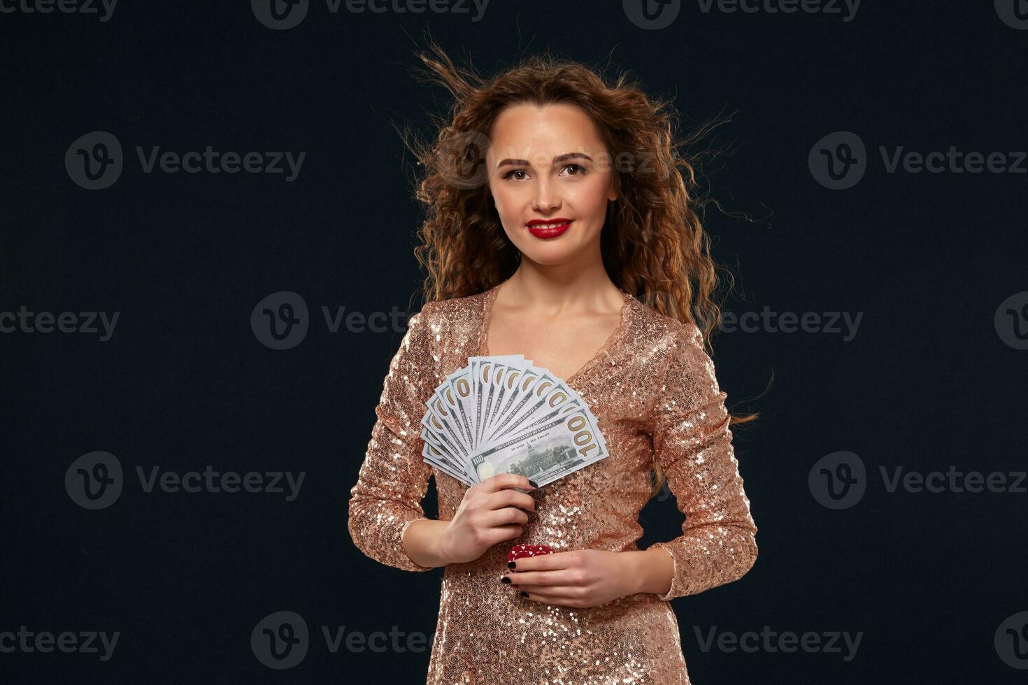 Image of lucky happy woman with brown long hair with fan of 100 dollar bills, lots of cash money, over black background photo