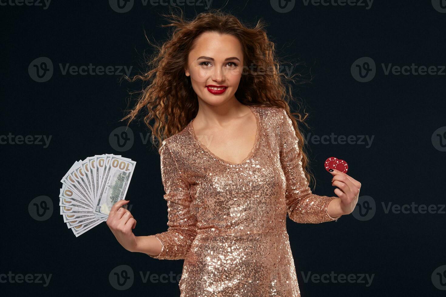 Image of lucky happy woman with brown long hair with fan of 100 dollar bills, lots of cash money, over black background photo
