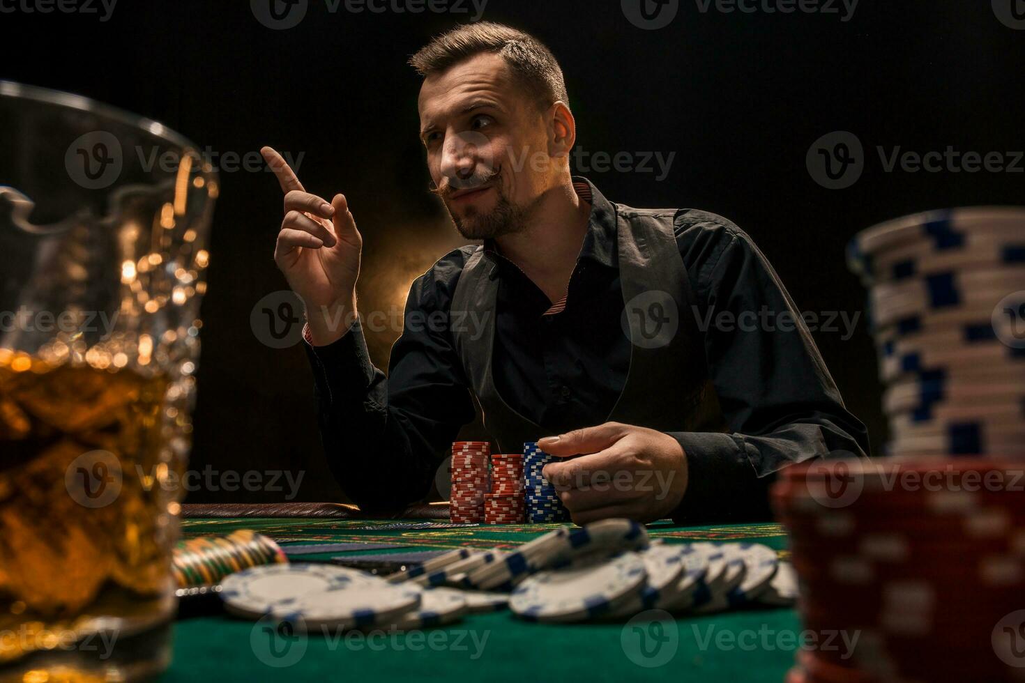 hombre es jugando póker con un cigarro y un whisky. un hombre victorioso todas el papas fritas en el mesa con grueso cigarrillo fumar. foto