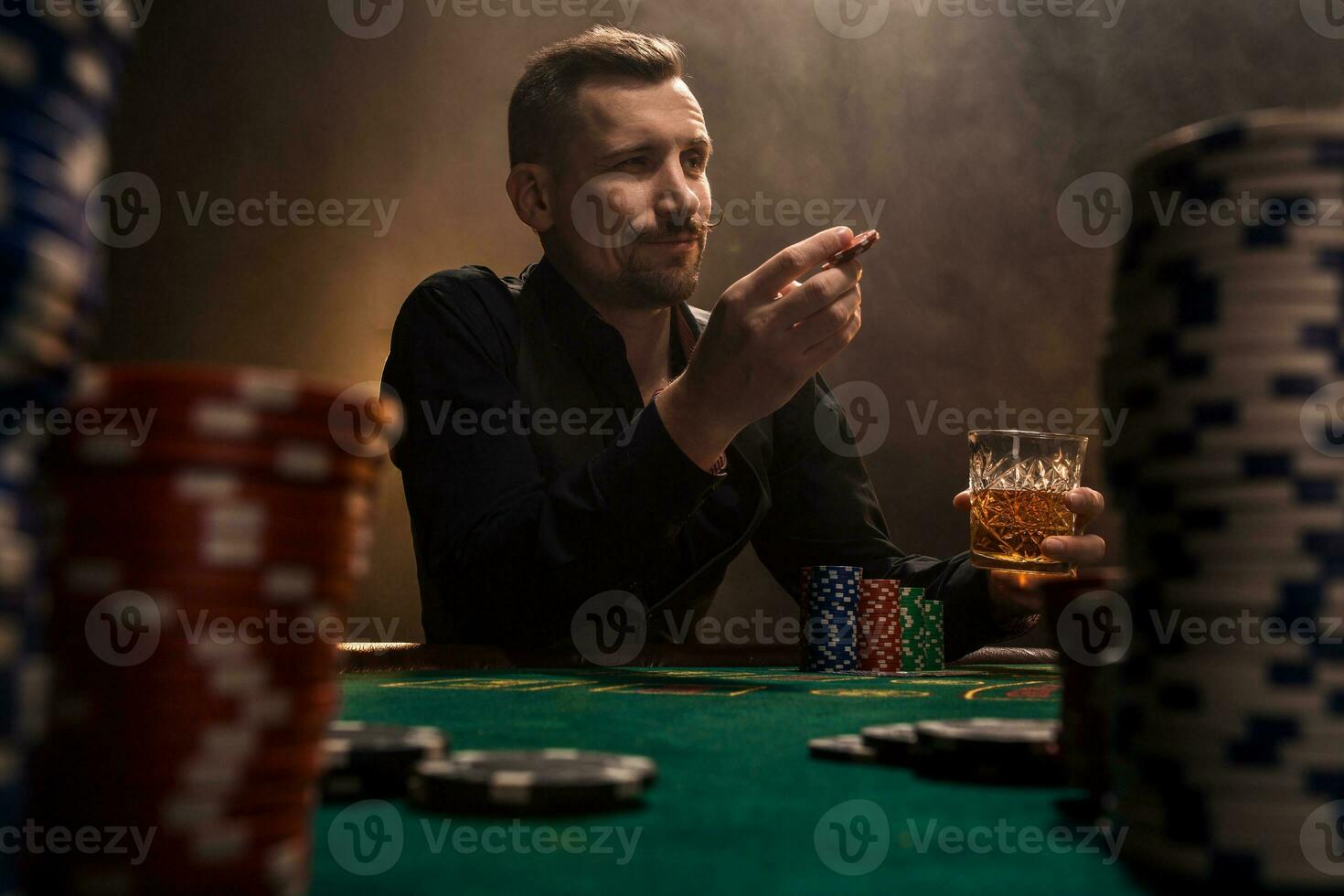 Young handsome man sitting behind poker table with cards and chips photo